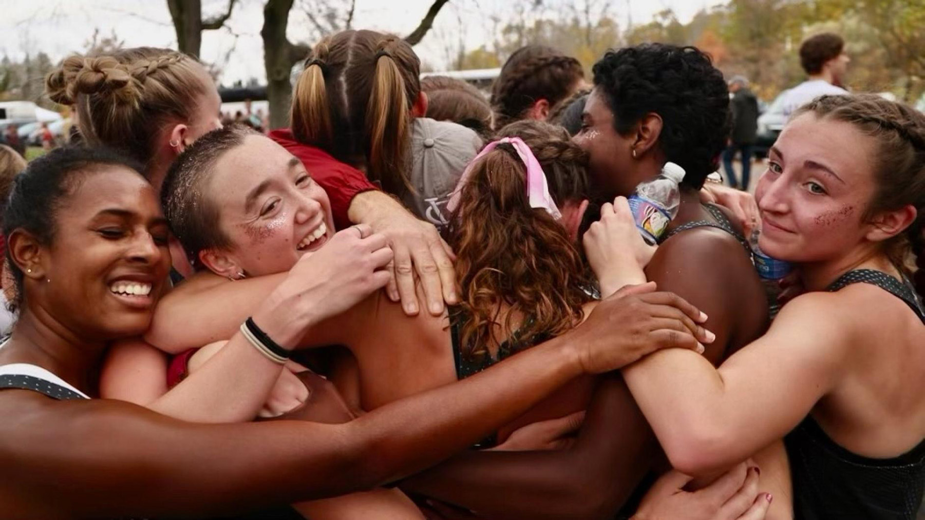 Large group of women athletes hugging in celebration.
