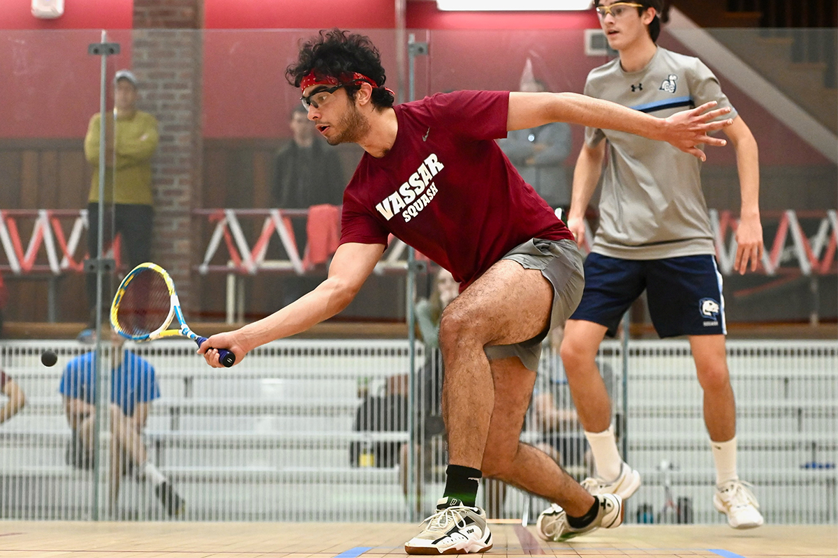 Action shot of Rithik Jalali bending down to hit the ball with his racket