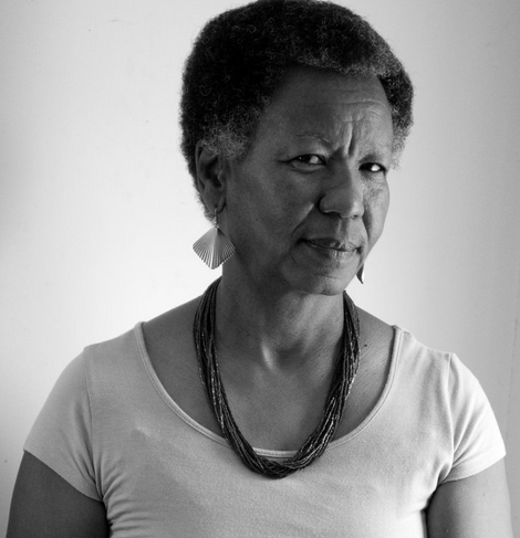 Portrait with white shirt, thick-beaded necklace, in a black and white image.