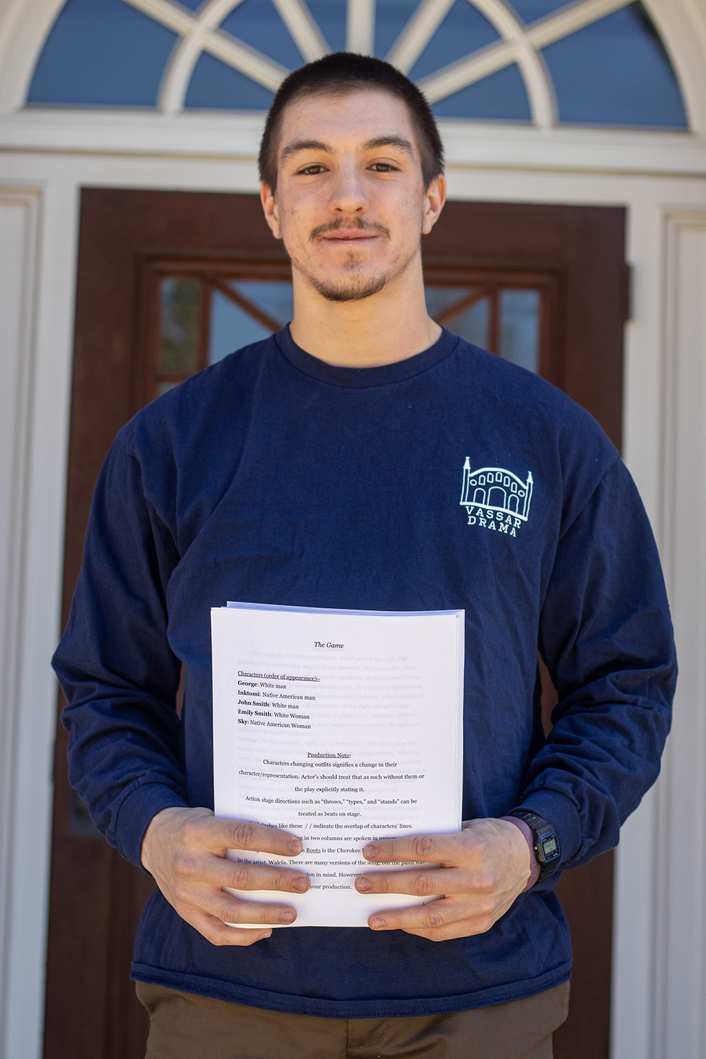A person with short hair including facial hair, wearing a blue sweatshirt holding a script.