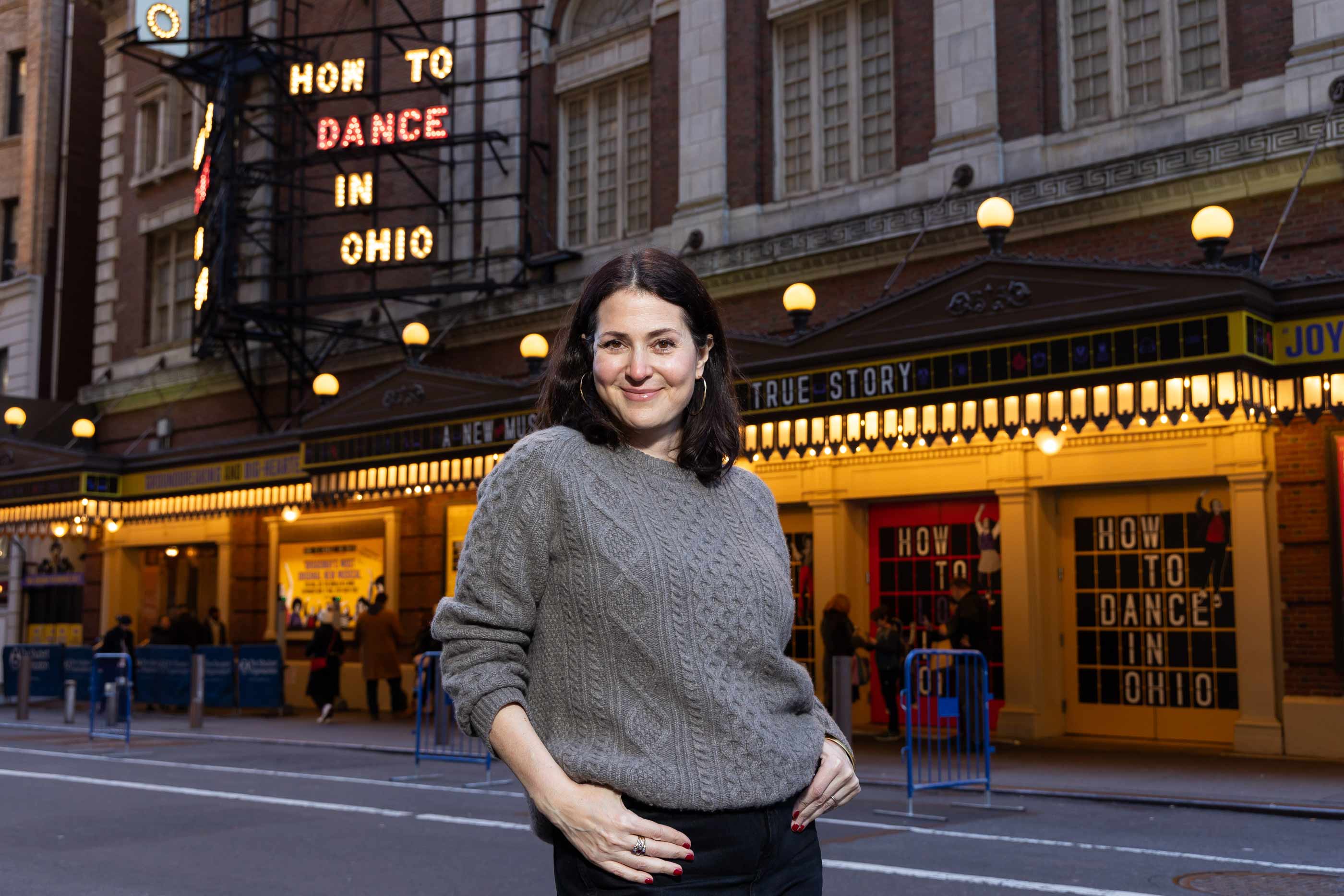 A portrait photo of Alexandra Shiva ’95 in front of the Belasco Theater in Manhattan. 