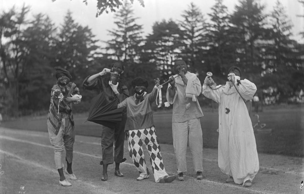 A black-and-white historical photo of Vassar students in racist costumes, performing outside.