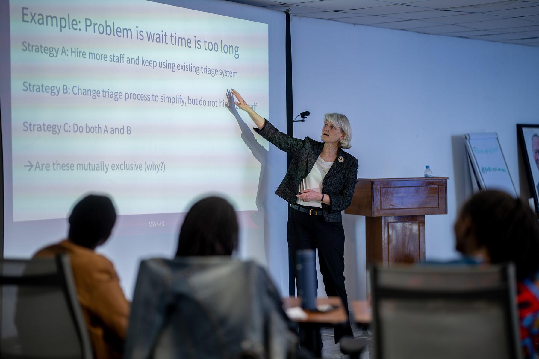 Pictured: Elizabeth Bradley. Standing in front of a classroom of seated students pointing at a projected image on a screen.