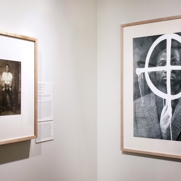 A closeup of the corner of an art gallery, with two abstract monochrome photos, one on each wall.
