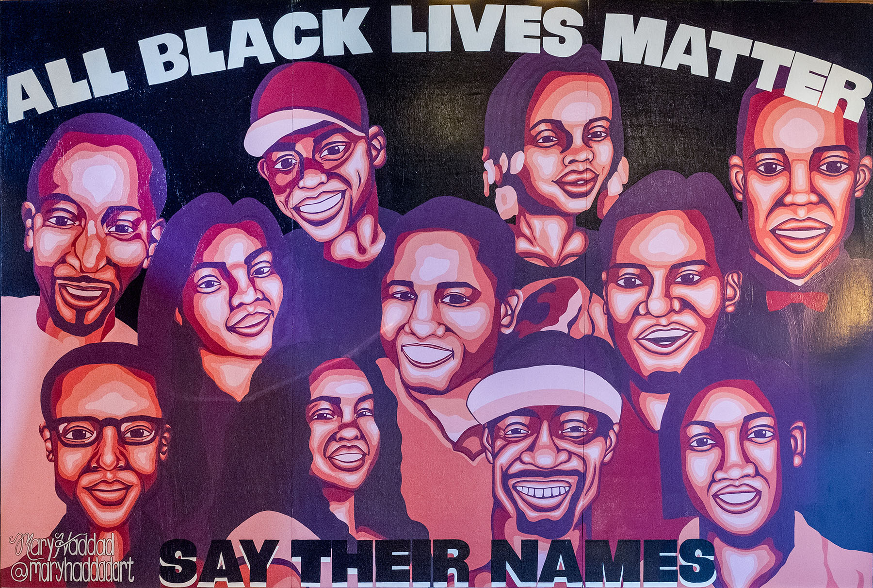 A mural with eleven faces of those representing the Black Lives Matter movement. Text at the top reads, "All Black Lives Matter." Text at the bottom reads, "Say Their Names."