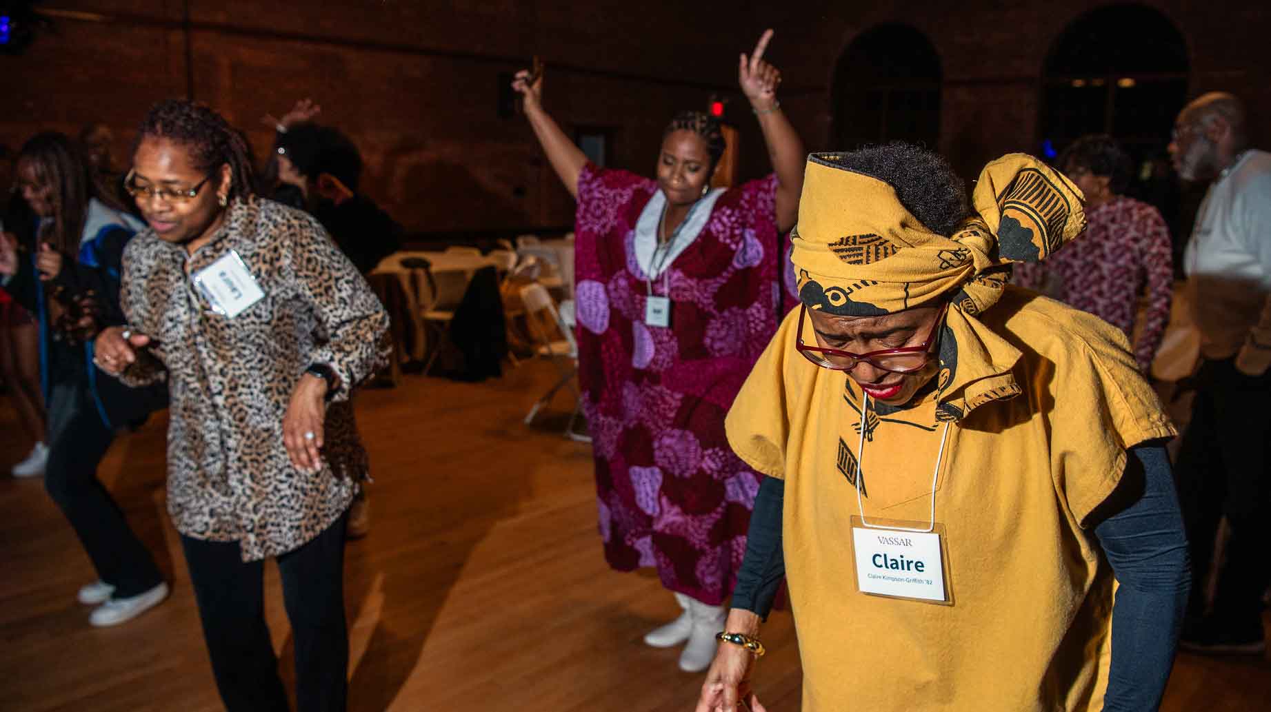 Three people dancing. One person has their hands raised while the two others are looking down.