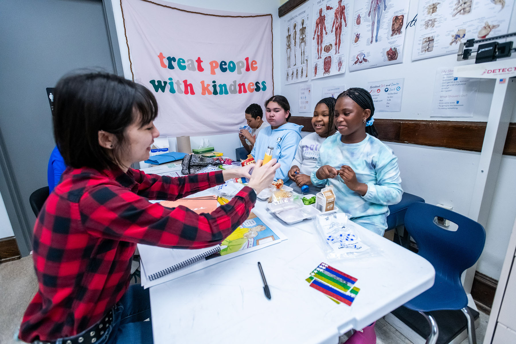 Rileigh Chinn ’25 sits with a group of students at a table, engaging in a discussion on the use of an inhaler with medical diagrams in the background.