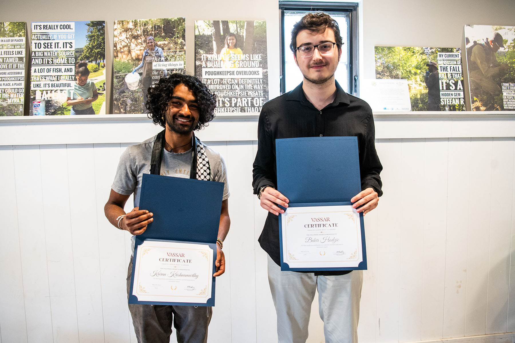 Two people holding diploma/awards and smiling.