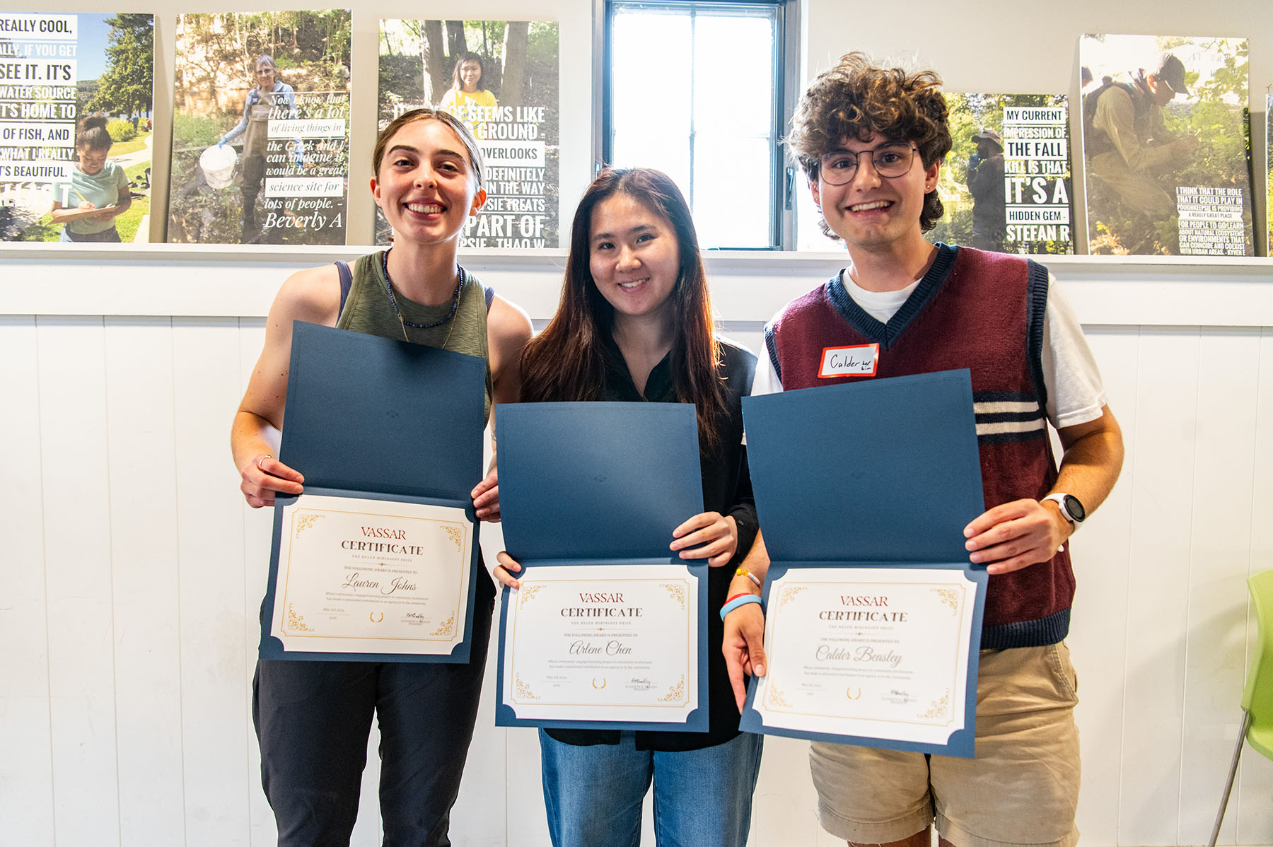 Three people holding diploma/awards and smiling.