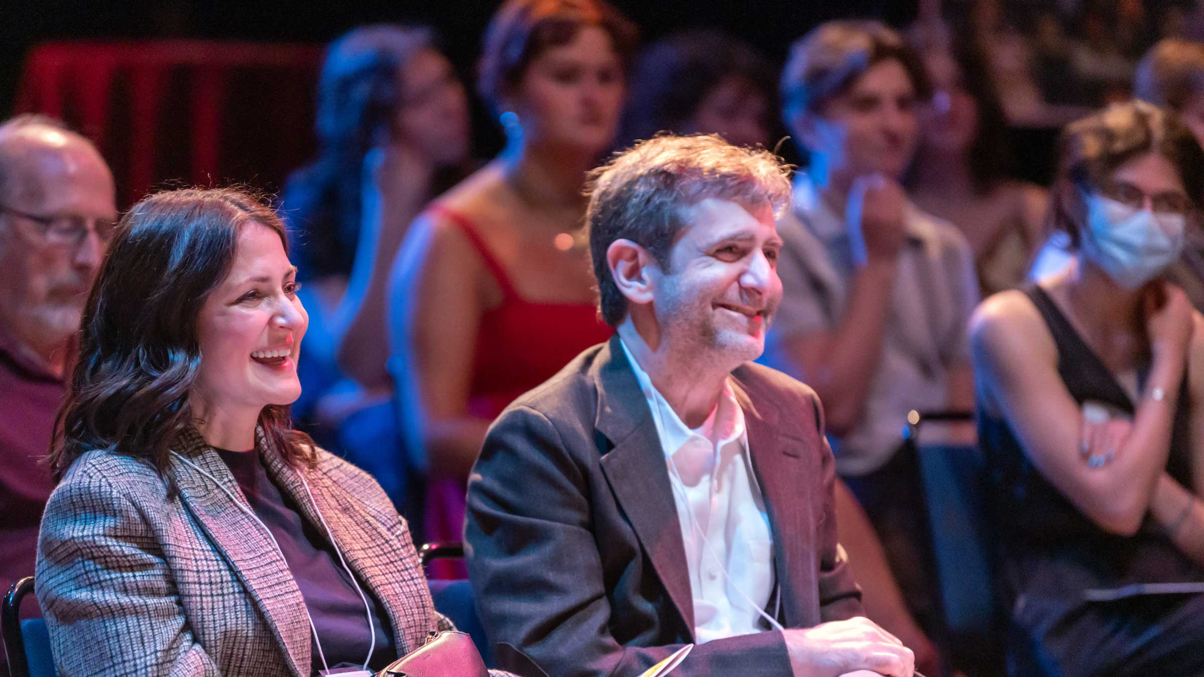 People seated in an audience smiling.