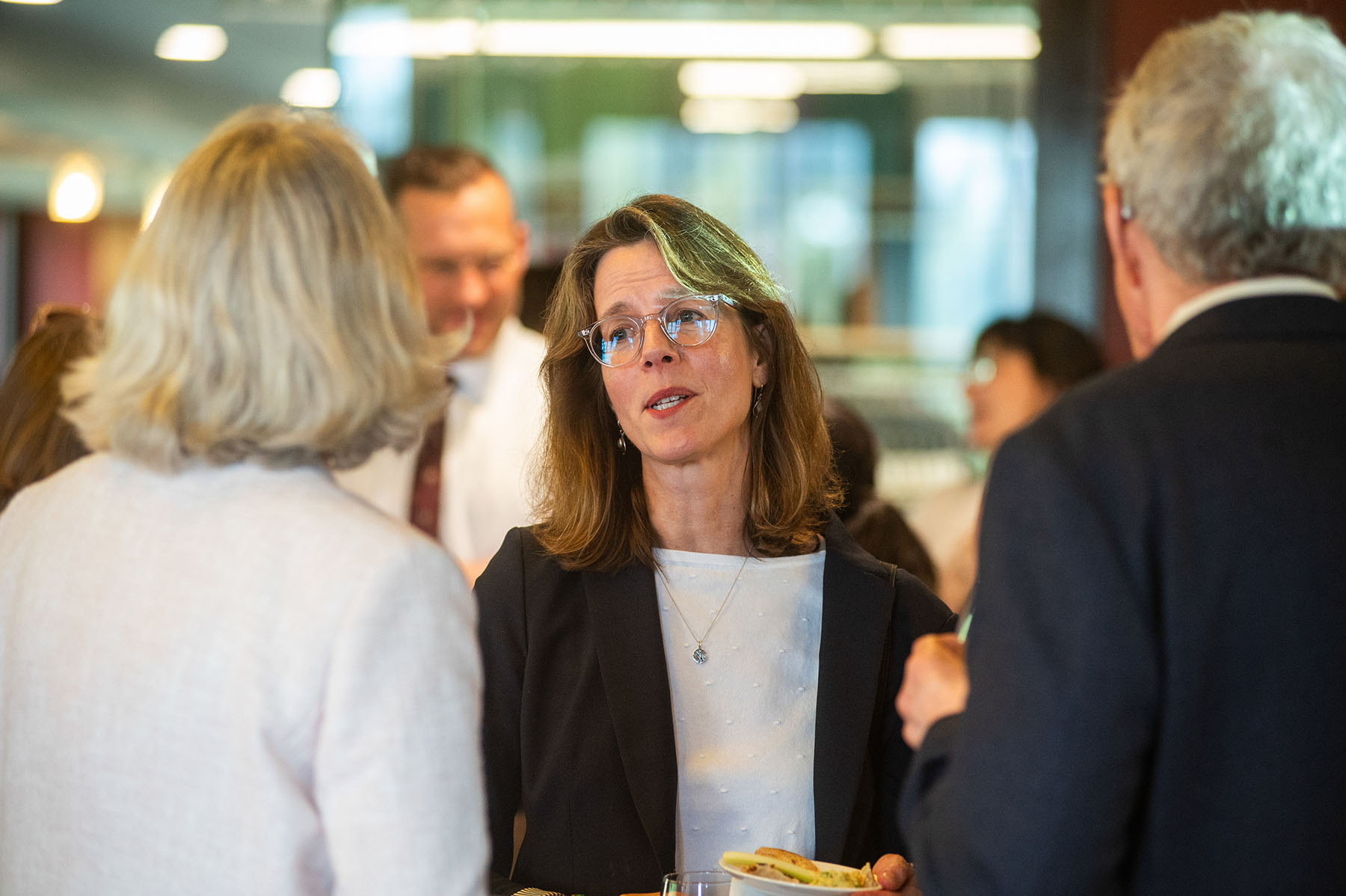 Professor of History Nancy Bisaha, wearing a white shirt and black jacket, talking with a crowd during an event.