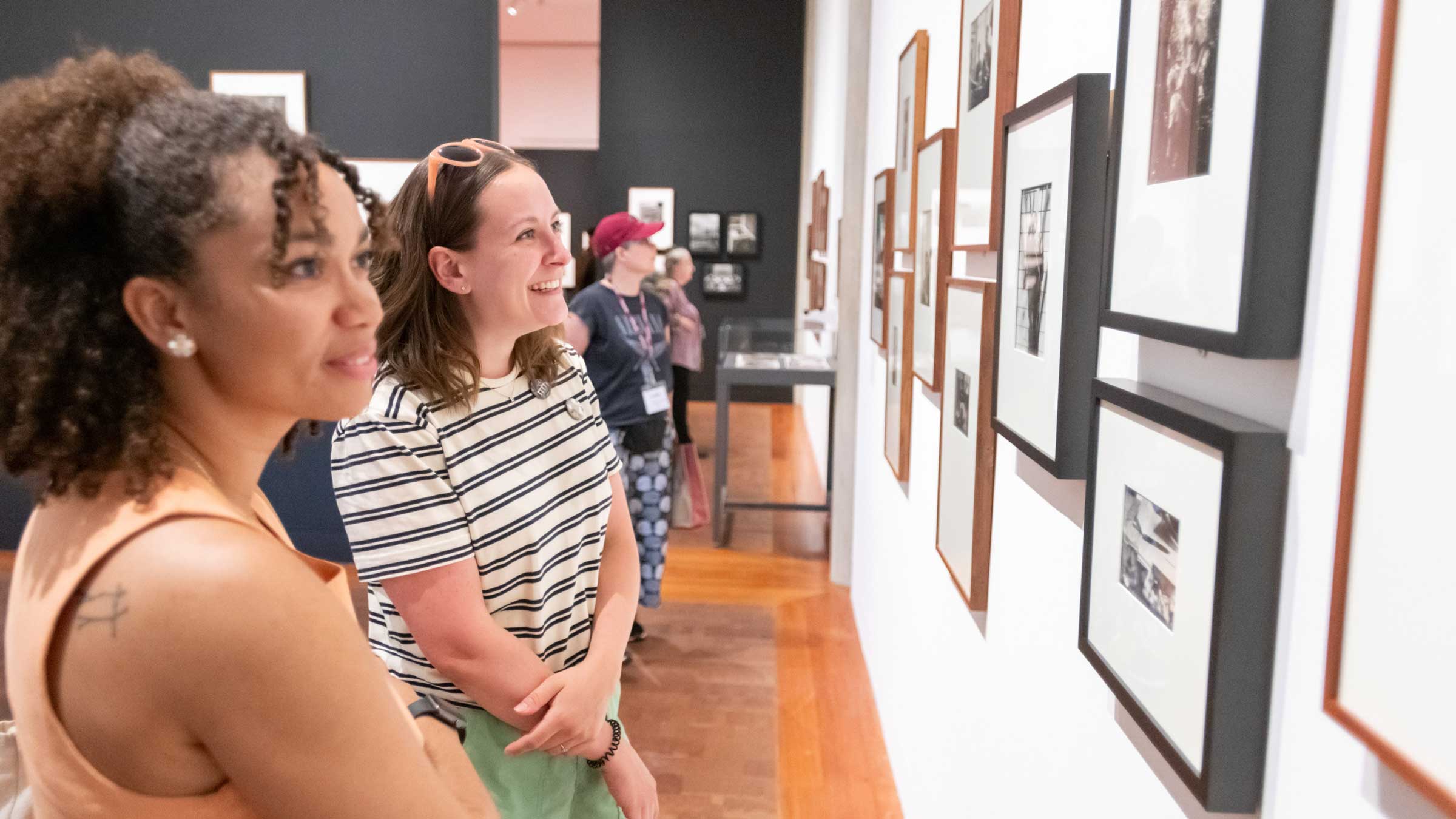 Two smiling people looking at art work on the wall of a gallery.