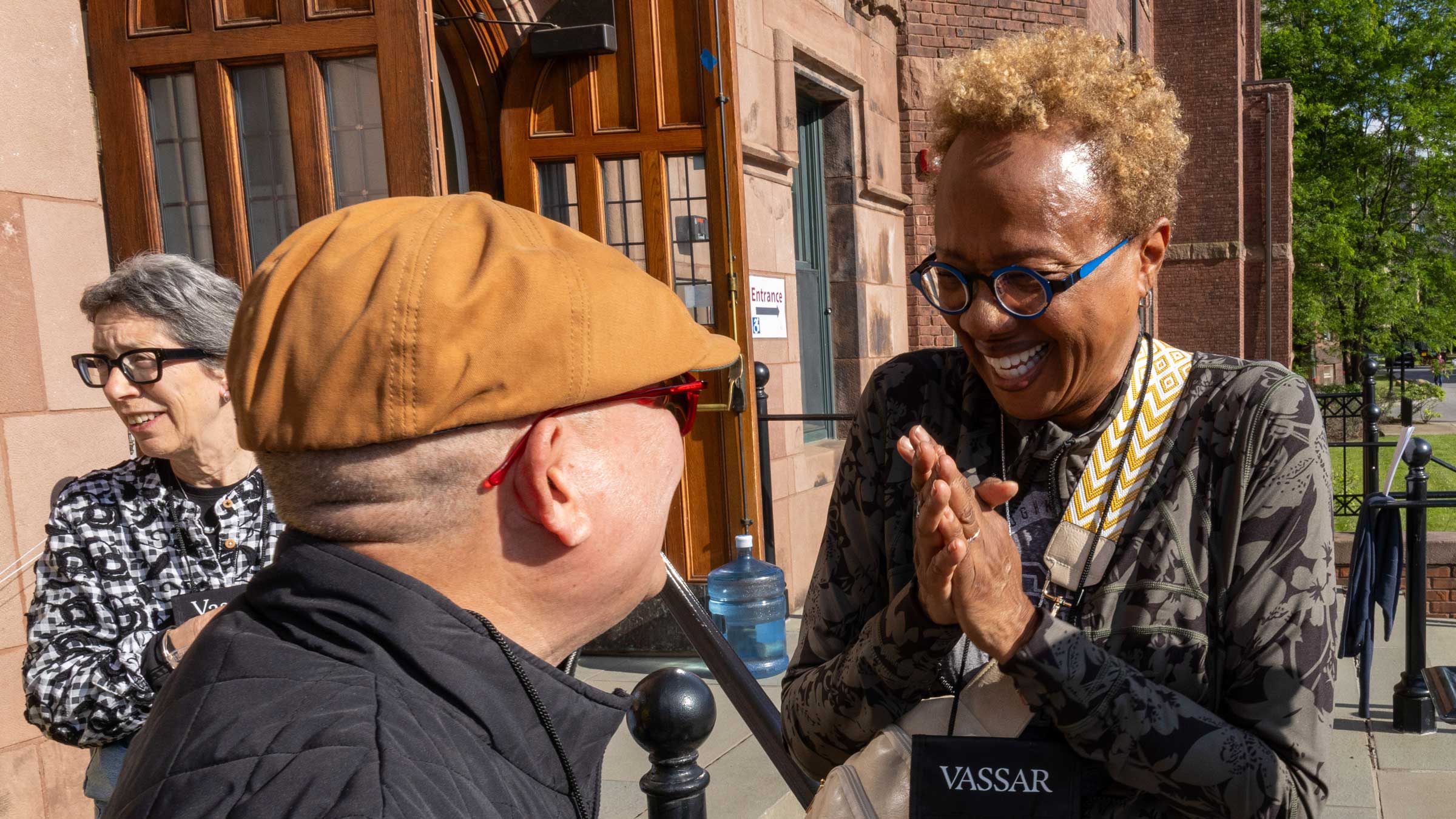 One person clasping hands and smiling at another person with their back to the camera.