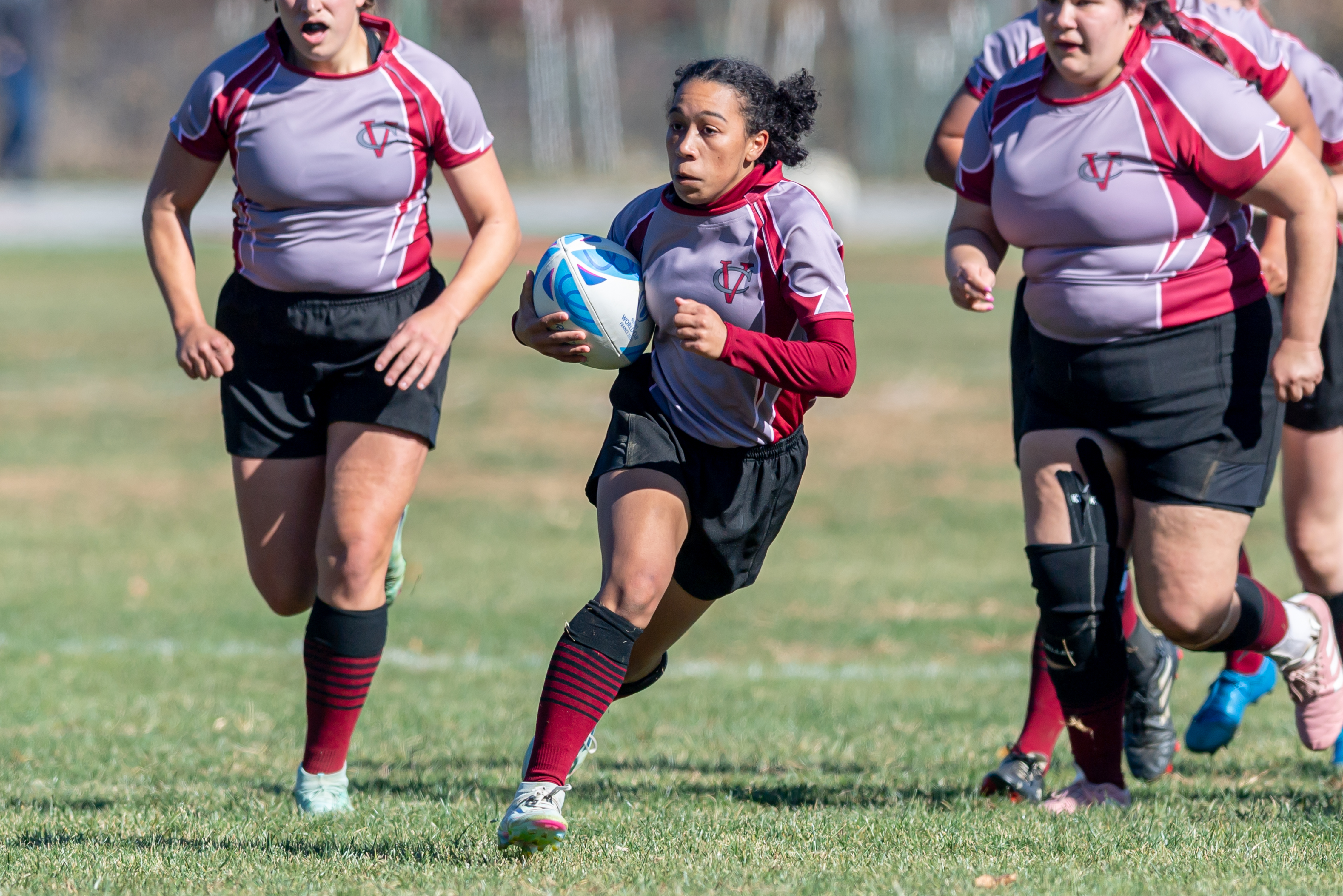 A rugby player running with the ball on a field.
