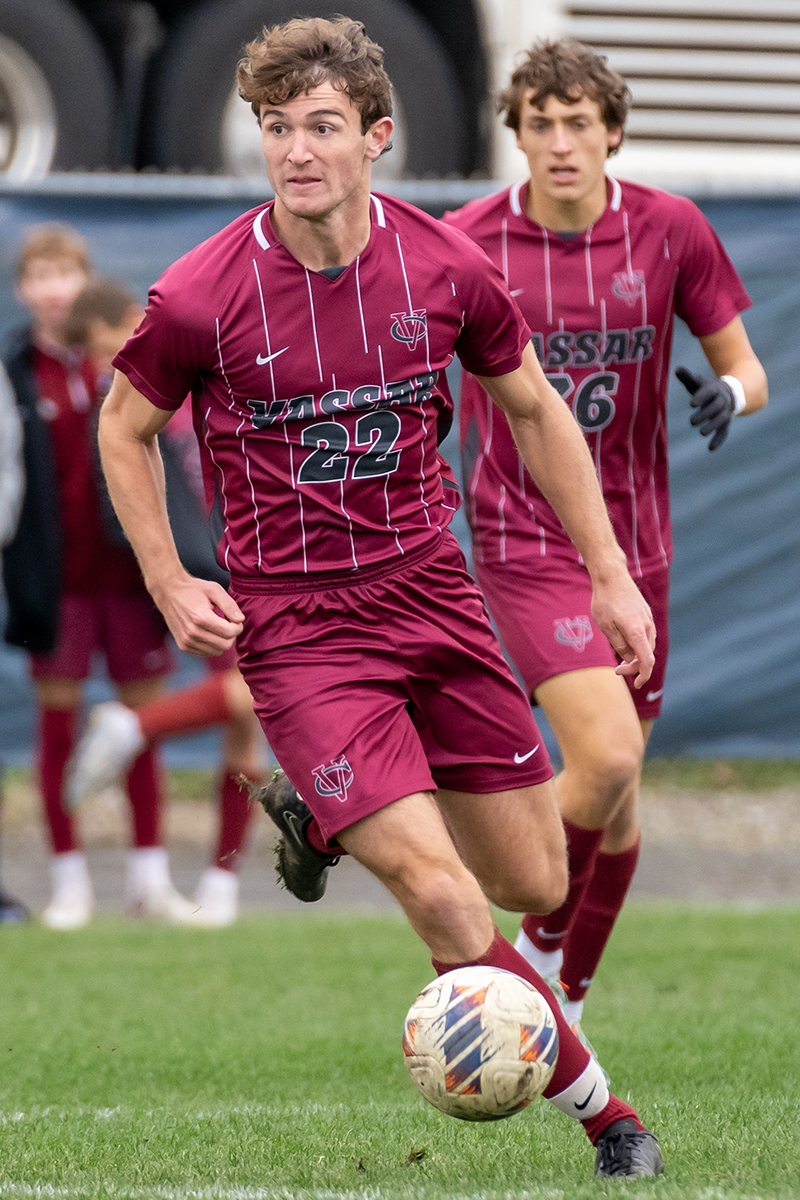 Closeup of a soccer player with an intense facial expression dribbling the ball during a game.