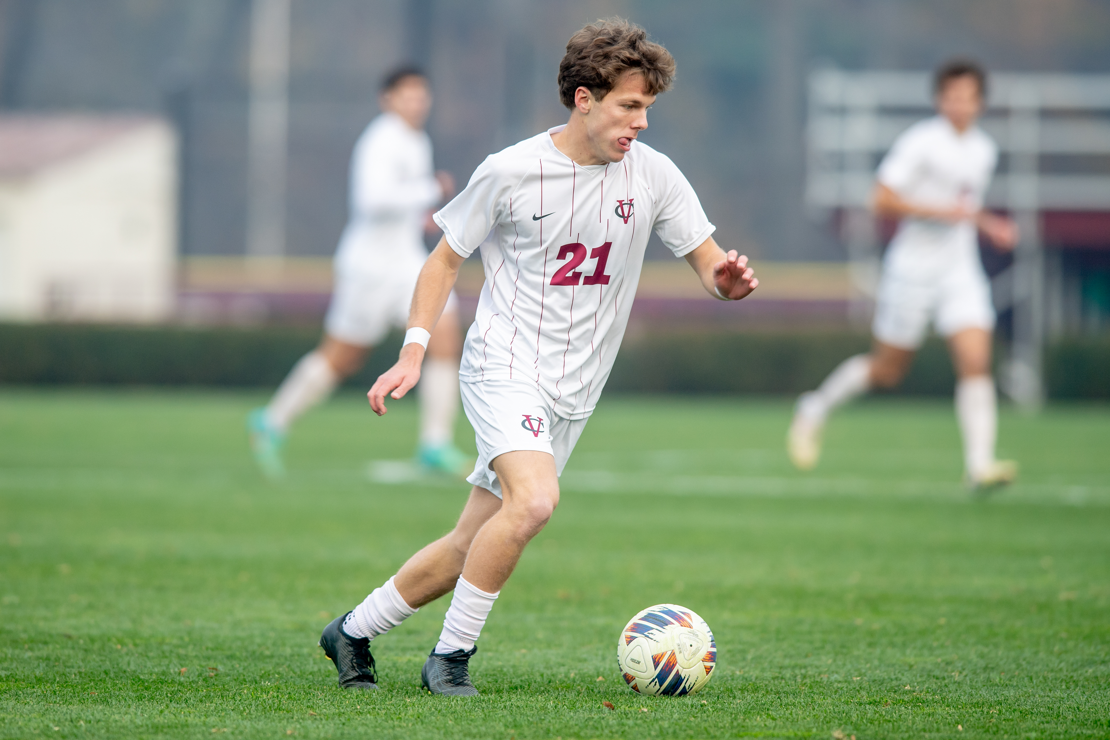 A soccer player runs toward the ball on a grassy field.