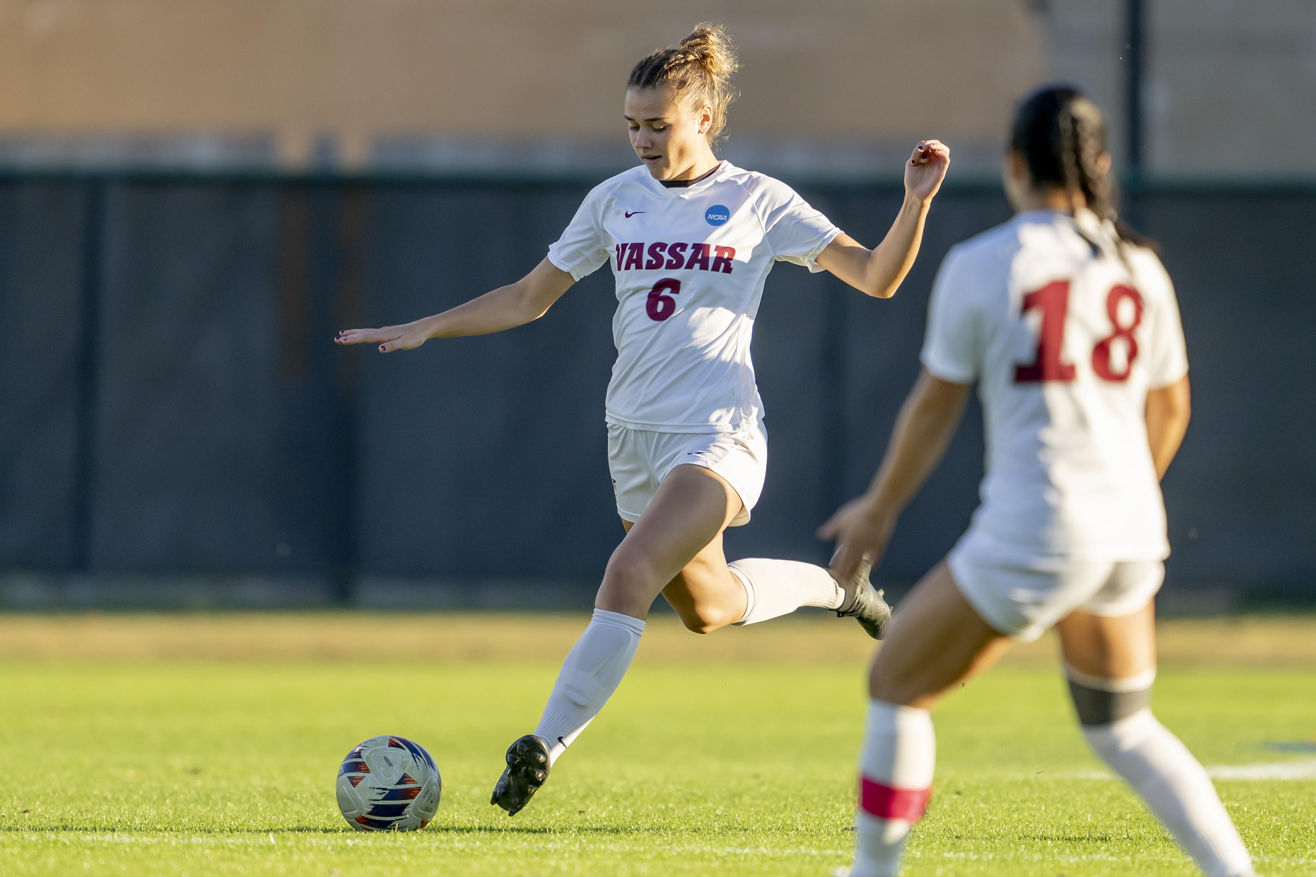 A soccer player kicks a ball on a grassy field.