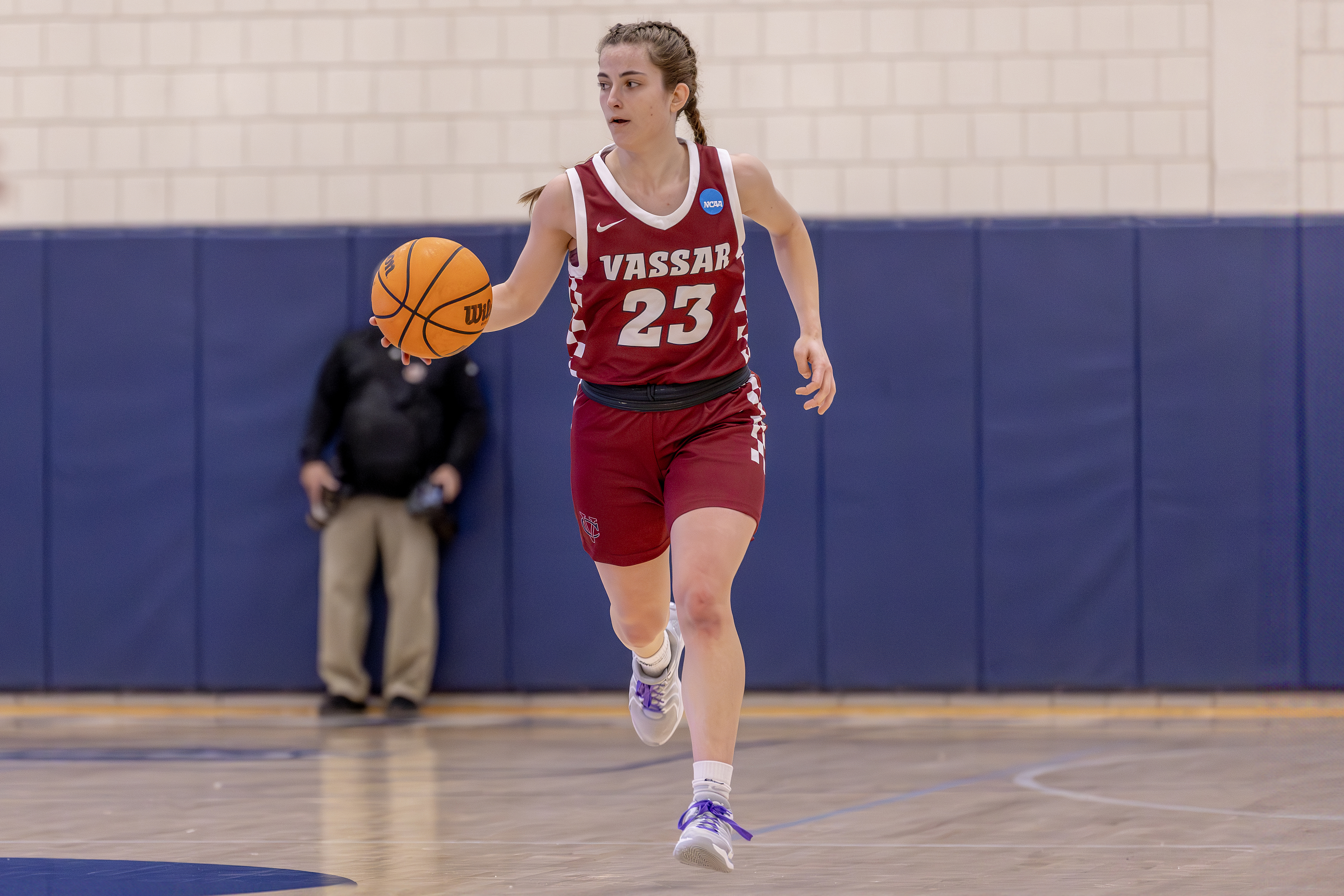 A basketball player dribbles the ball on an indoor court.
