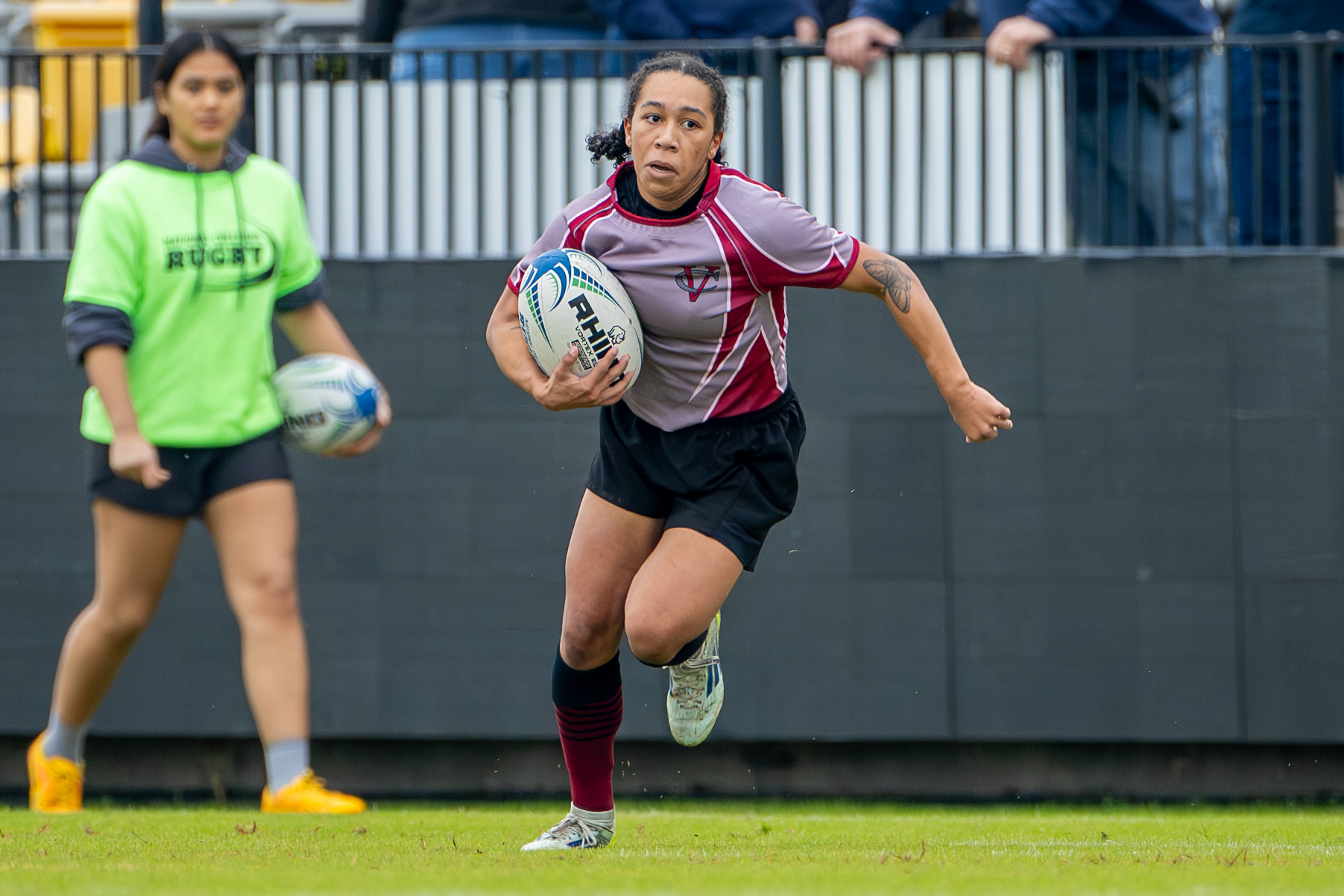 A rugby player runs with the ball on a field during a match.