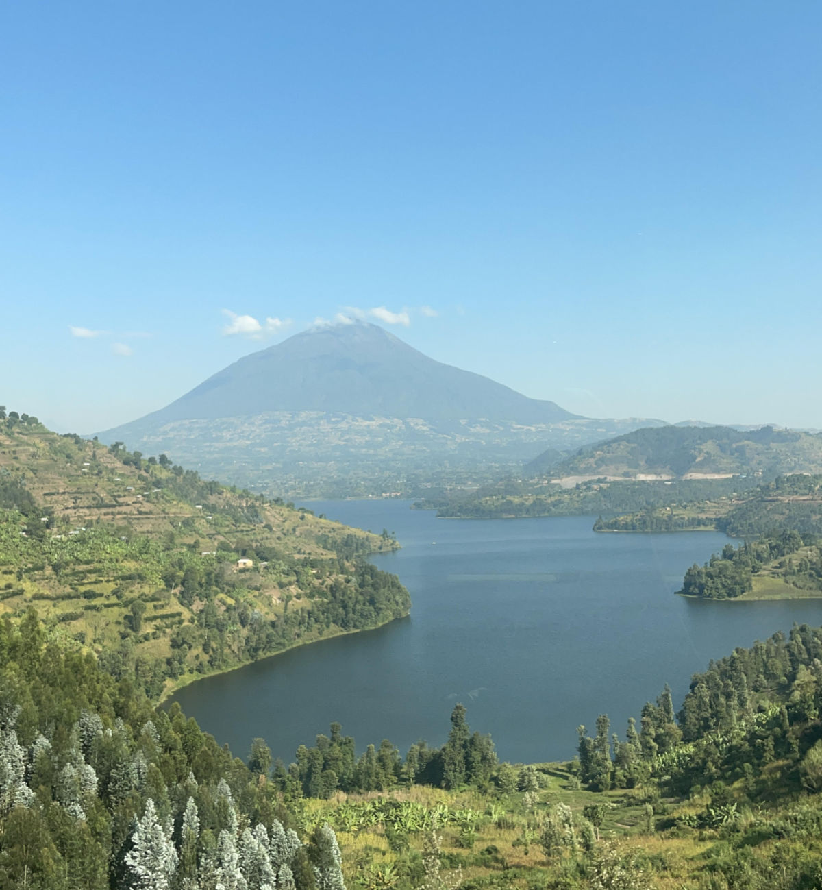 A photo of a green landscape under a clear blue sky with a river running through it and a mountain in the distance.
