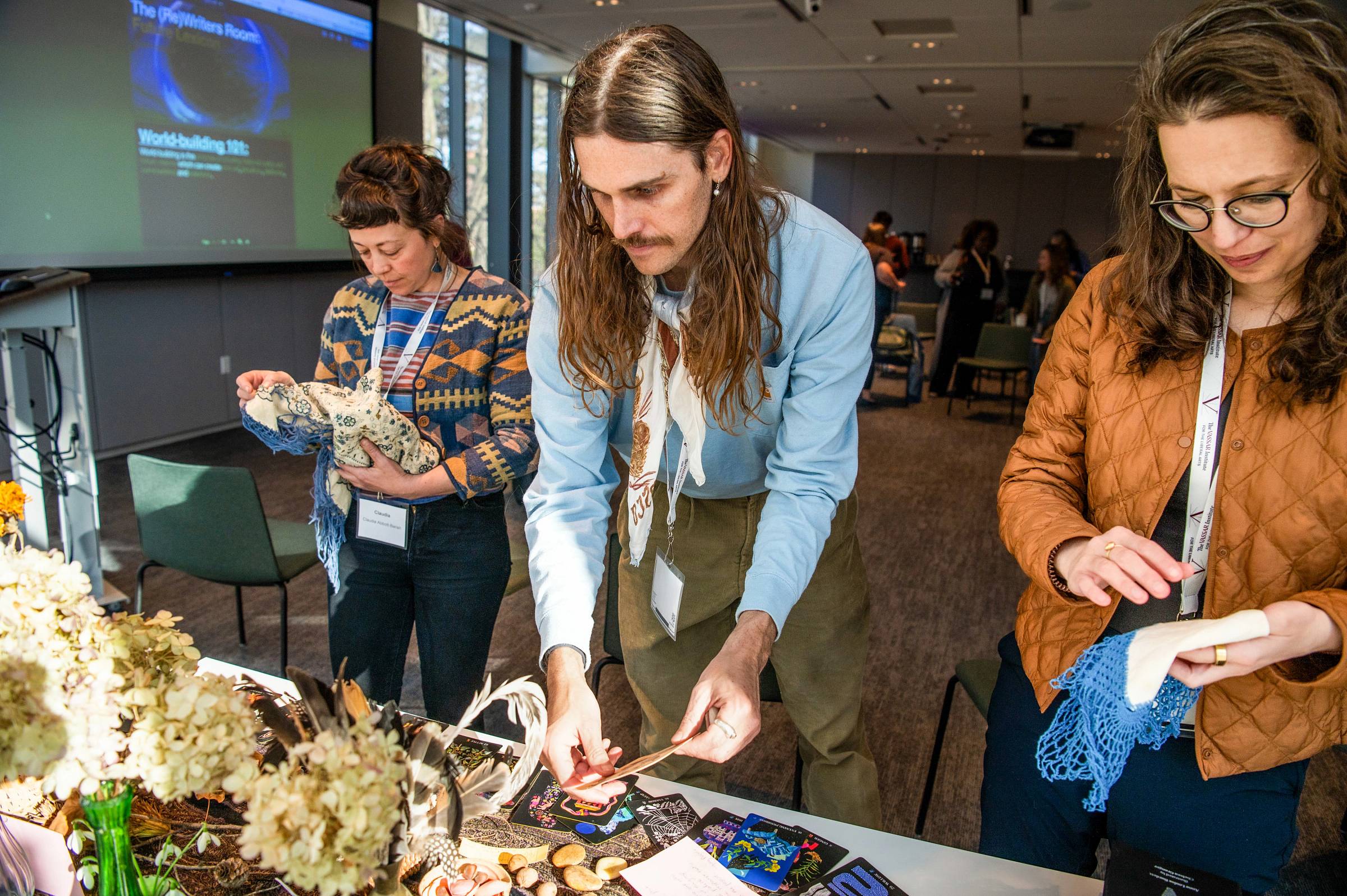 Three people at a craft table looking and various items.