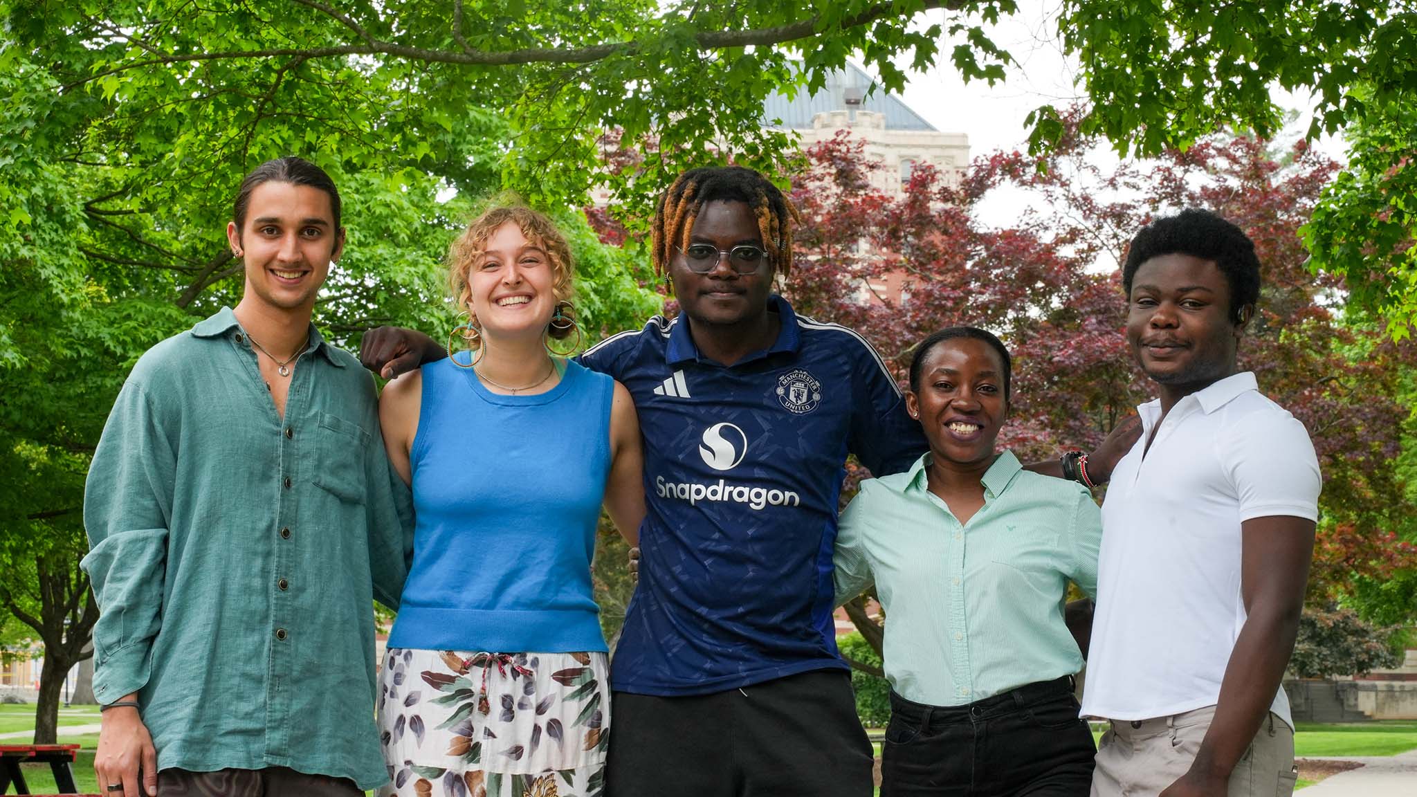 A group standing together smiling, with trees in the background.