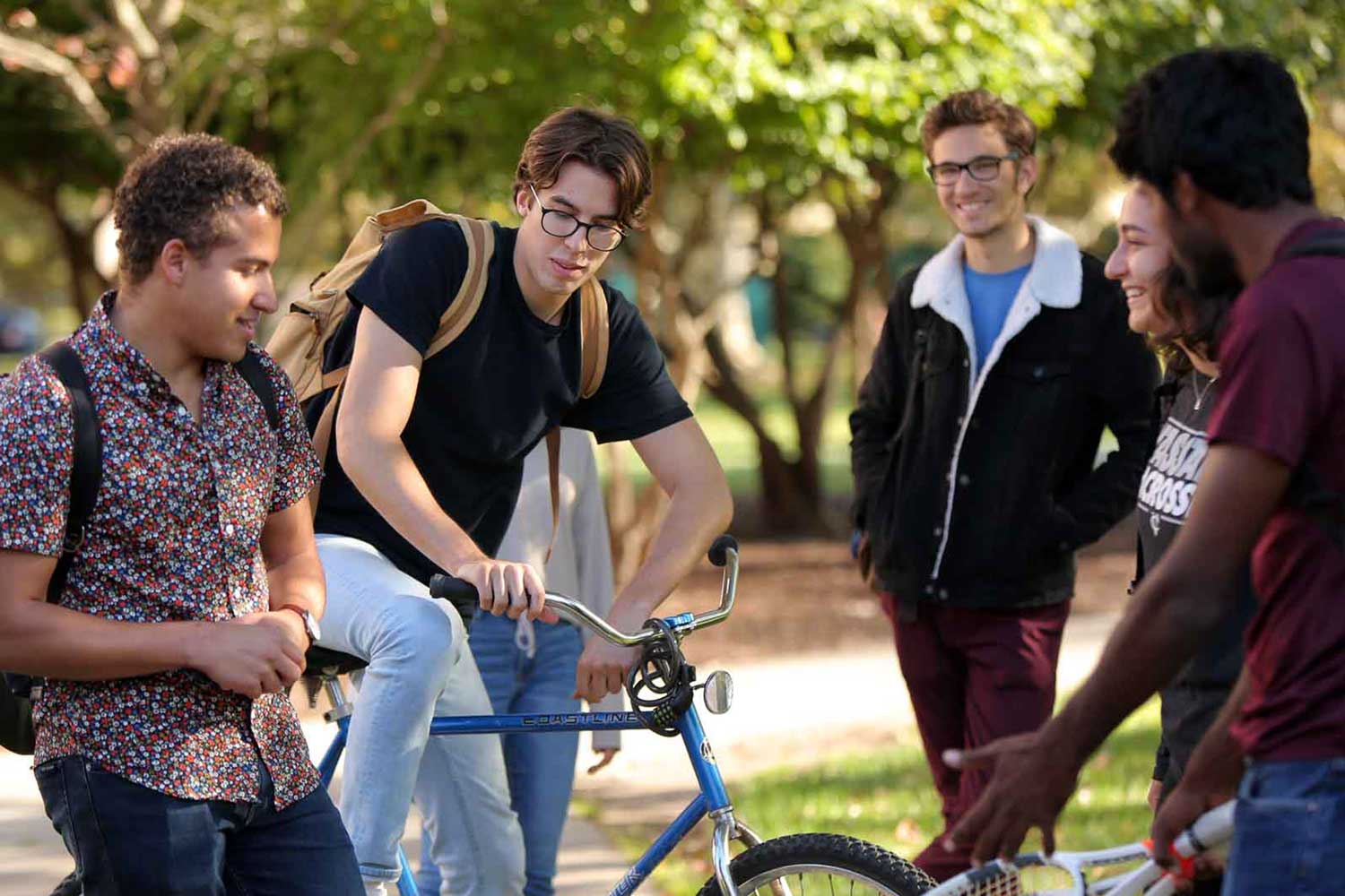 Group of people outside, some on bikes, chatting.
