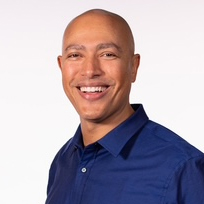 Person smiling for a portrait with a blue shirt on a white background.