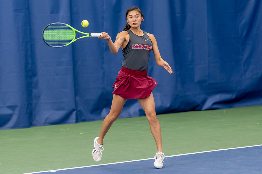A tennis player hits the ball on an indoor court