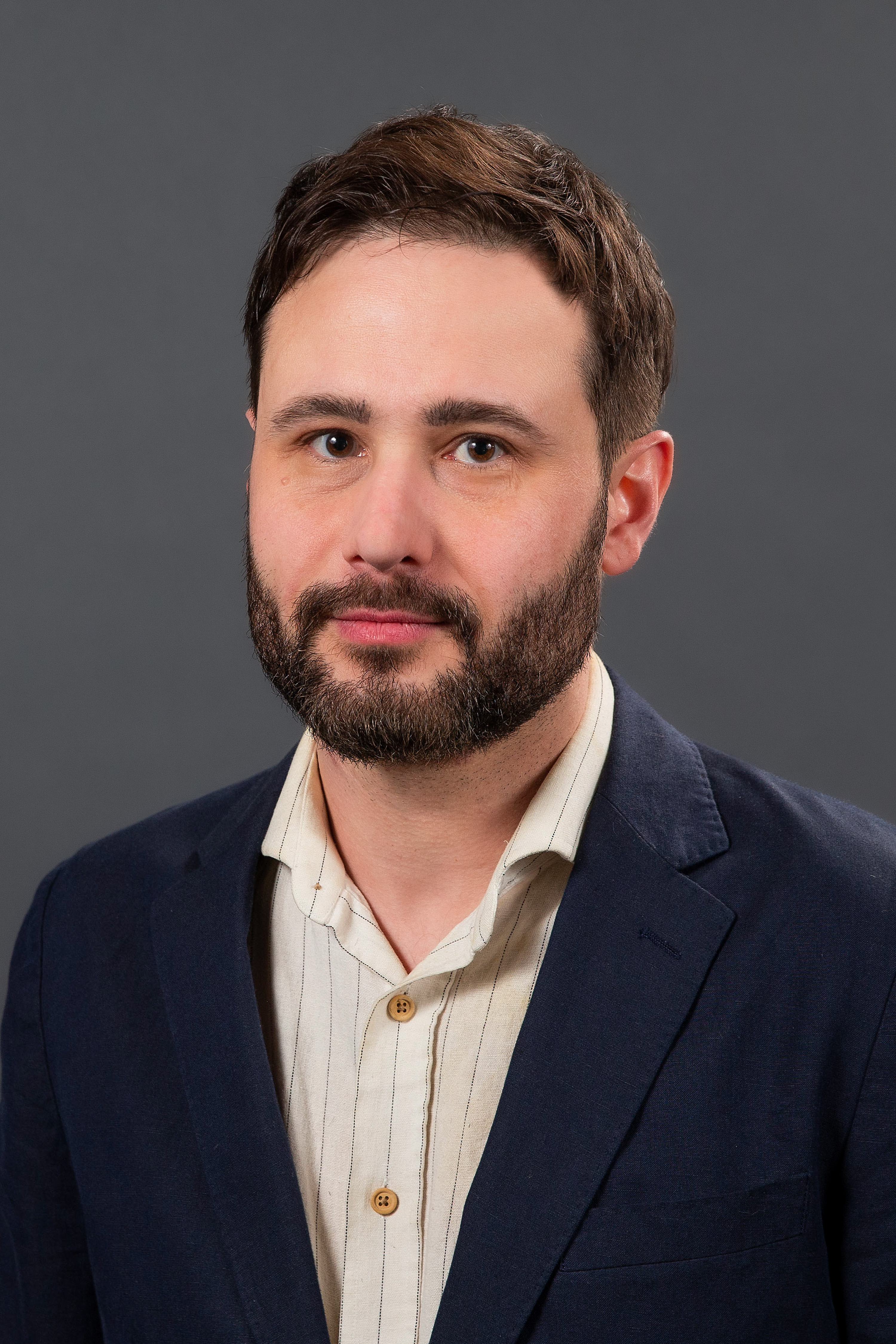 Studio portrait of a person in a suit jacket with no tie.