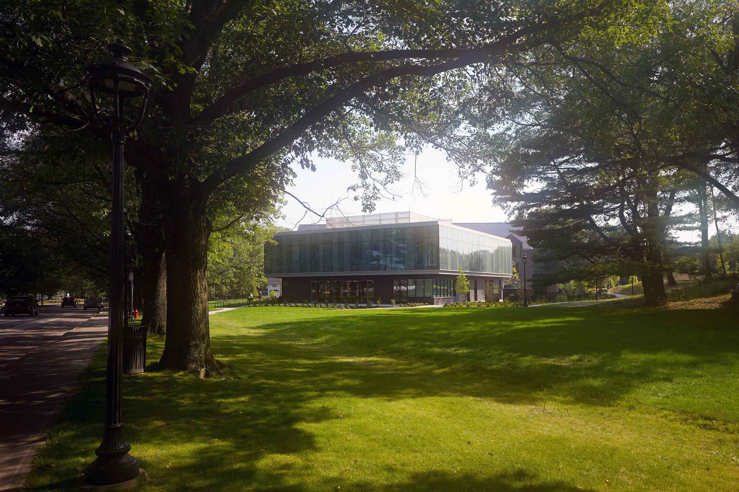 Exterior photo of a building surrounded by large trees and a grass lawn.