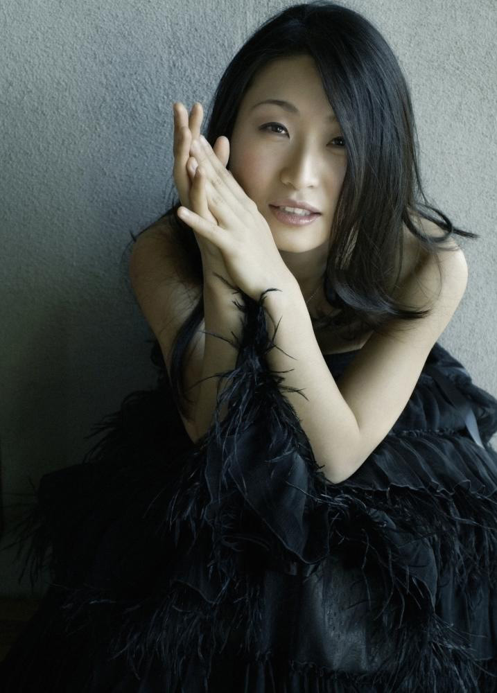 portrait-style image of subject holding hands together near face.