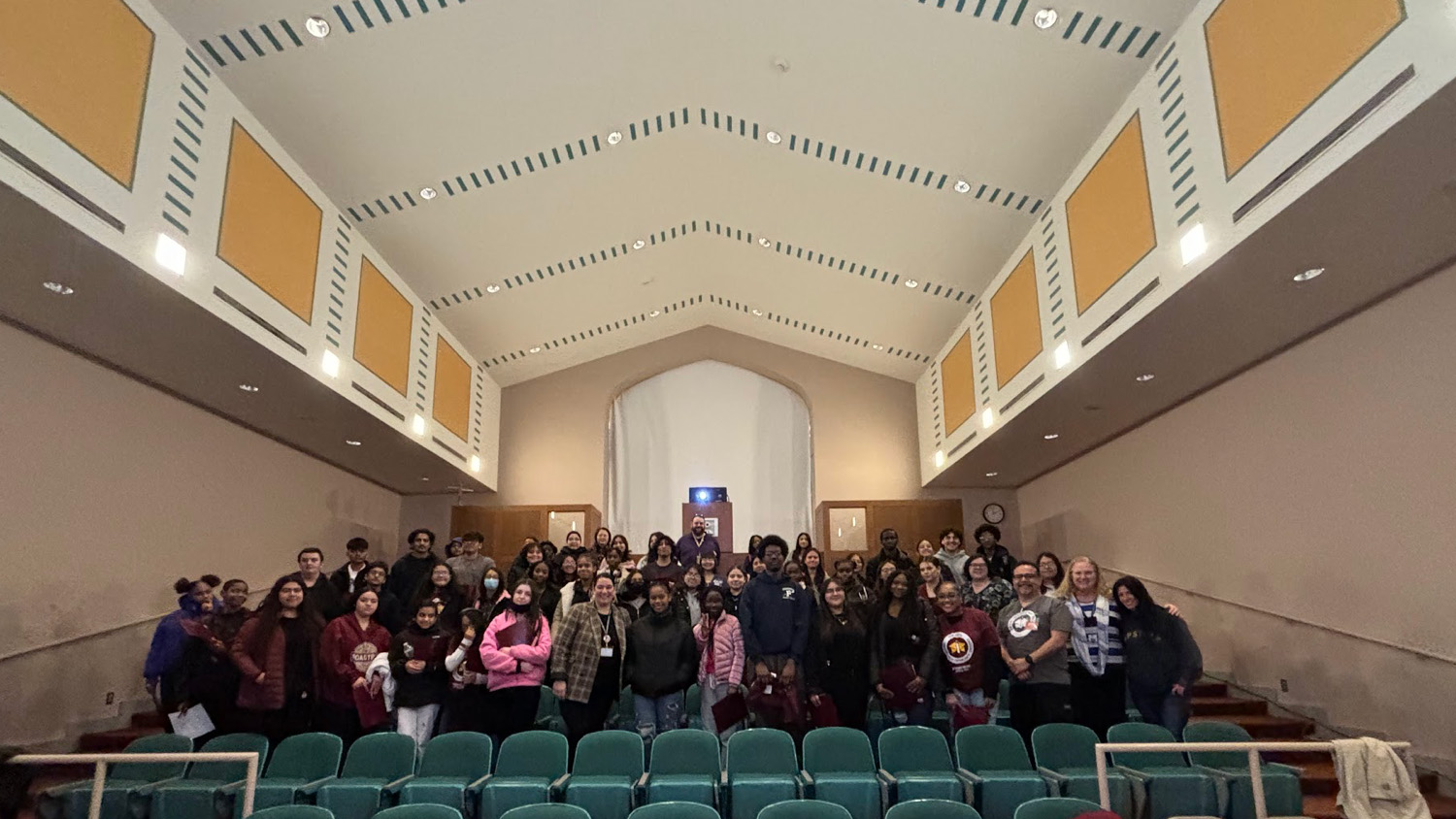 Large group of people standing in an auditorium. 