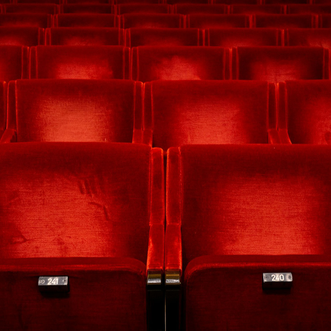 Red movie theater seats in the dark.