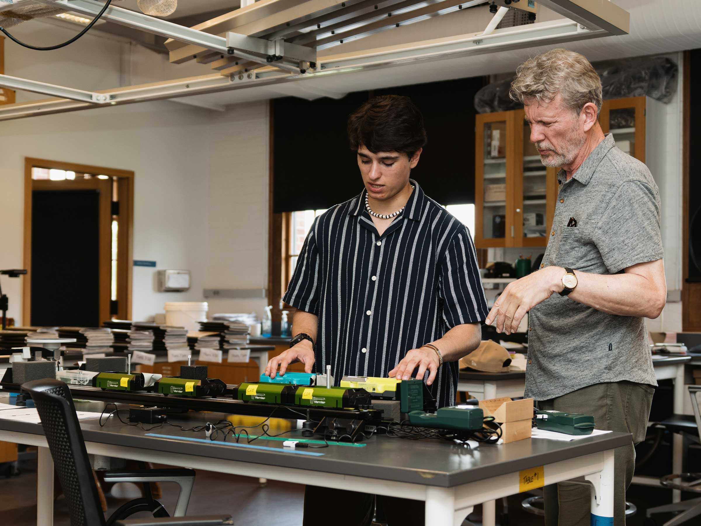 Two people standing at a table manipulating instruments.