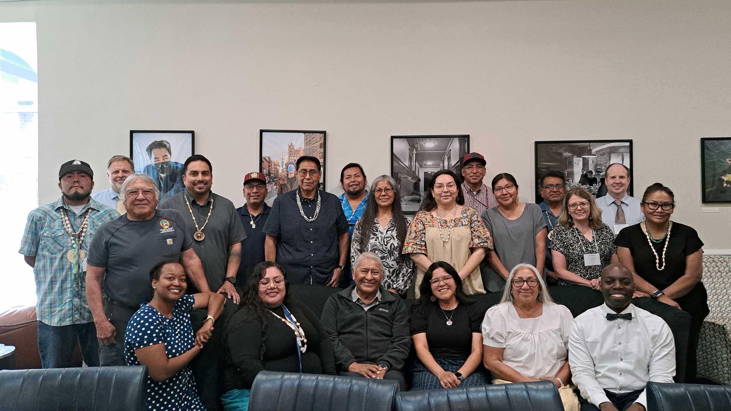 A large group of people, some seated while others stand smiling for a group photo.