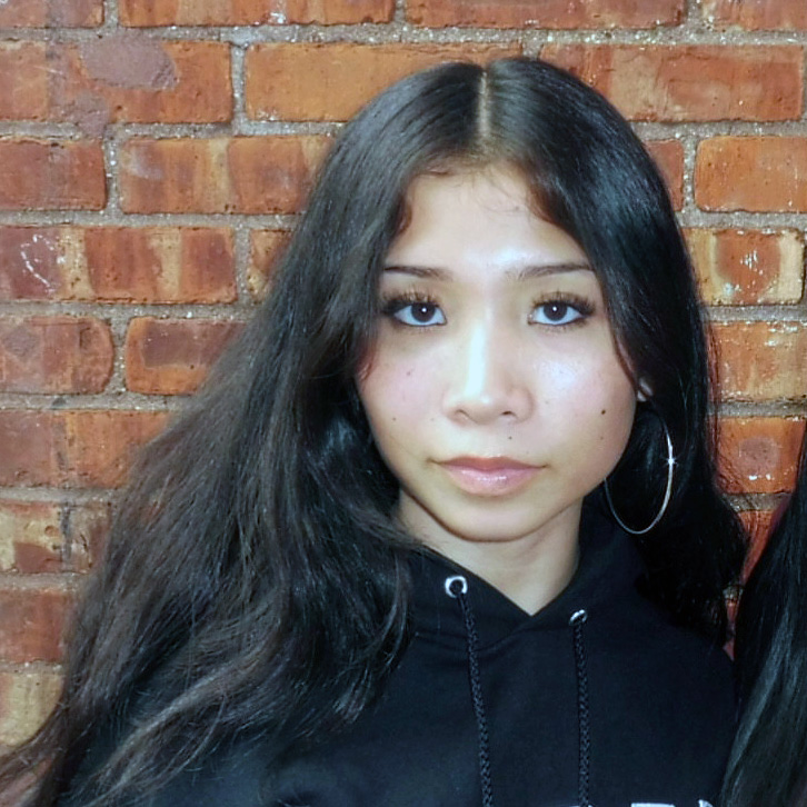 Photo portrait of a person standing in front of a brick wall.