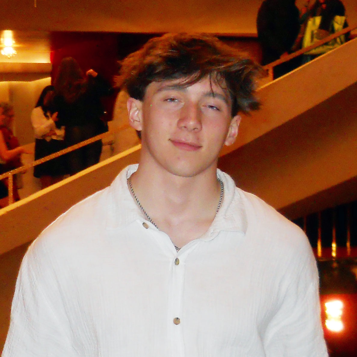 Photo portrait of someone in front of staircase in a dimly lit building.