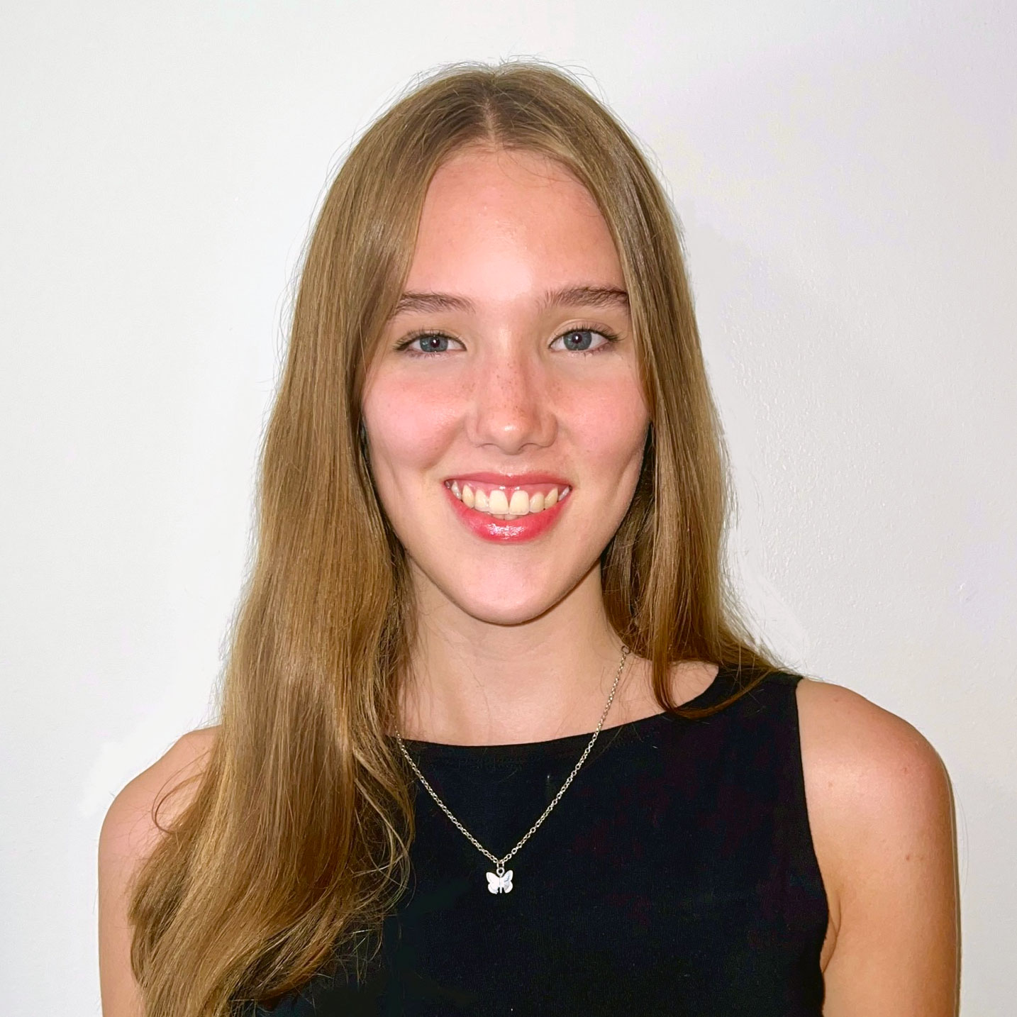 Photo portrait of a person standing in front of a white wall.