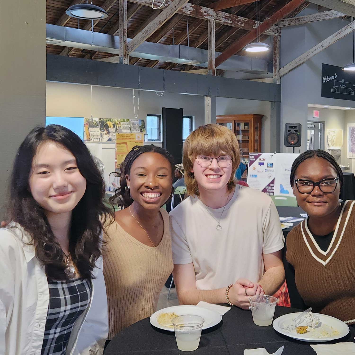 Four smiling people seated at a table with food.