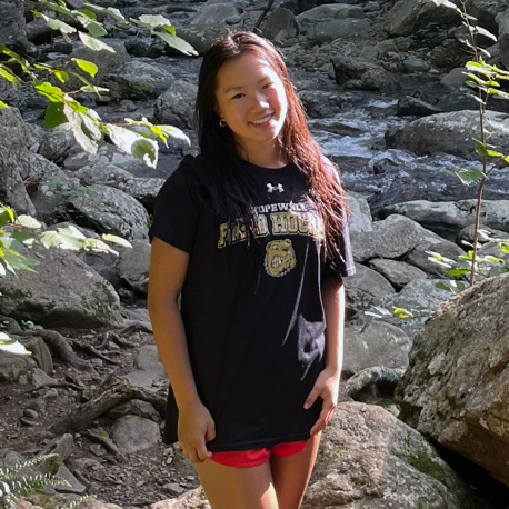 Photo of a person standing in a dry river bed with rocks.