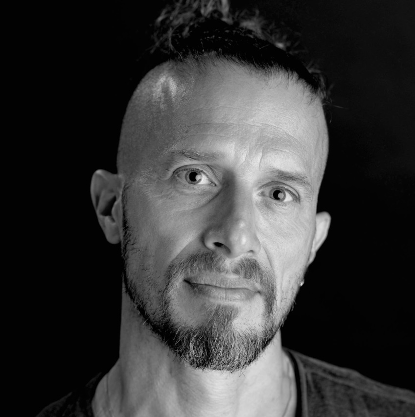 Photo portrait of a person standing in front of a black wall.