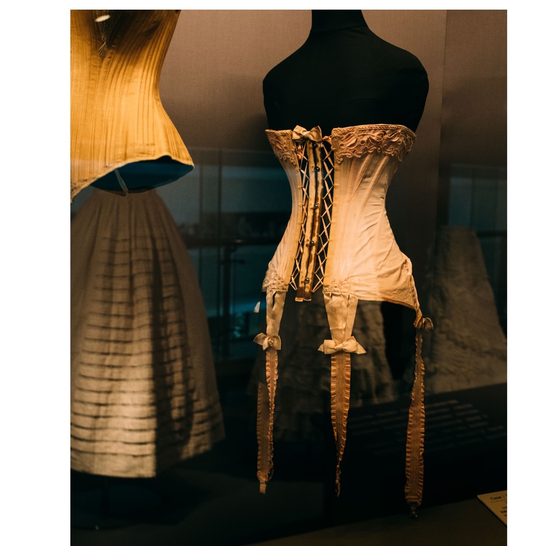 Detail photo of an antique corset, facing the ties, on a black velvet manequin.