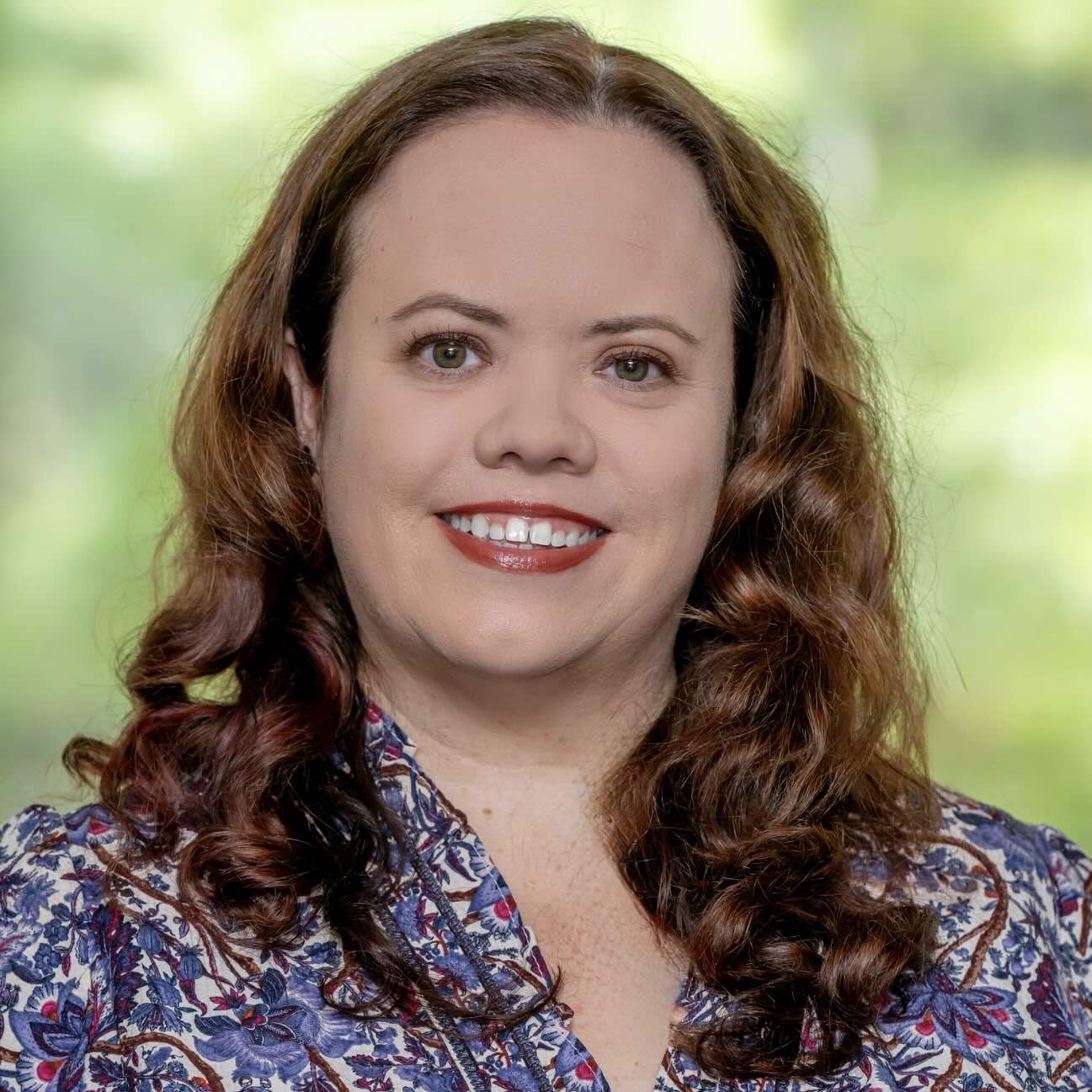 Photo portrait of a person standing in front of a green foliage.