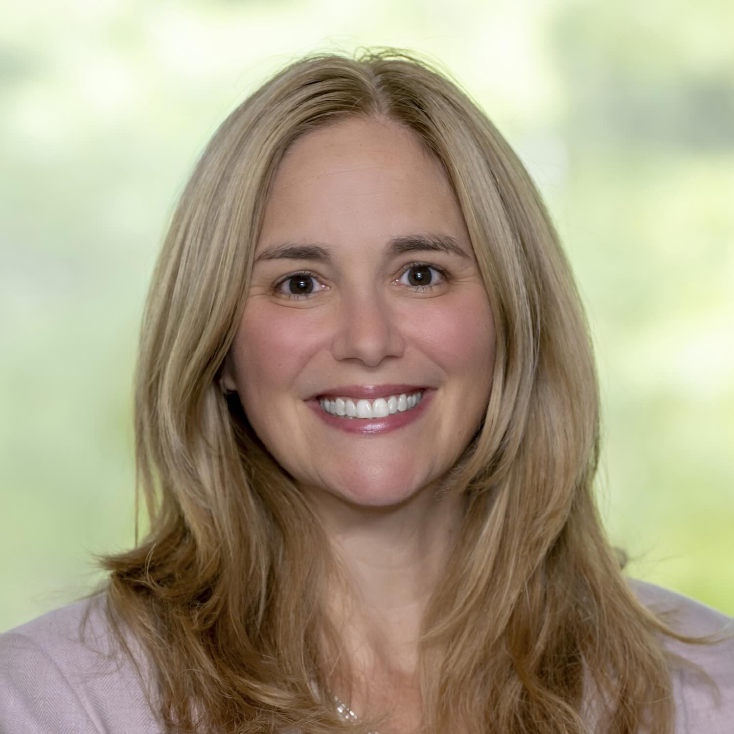 Photo portrait of a person standing in front of green foliage.