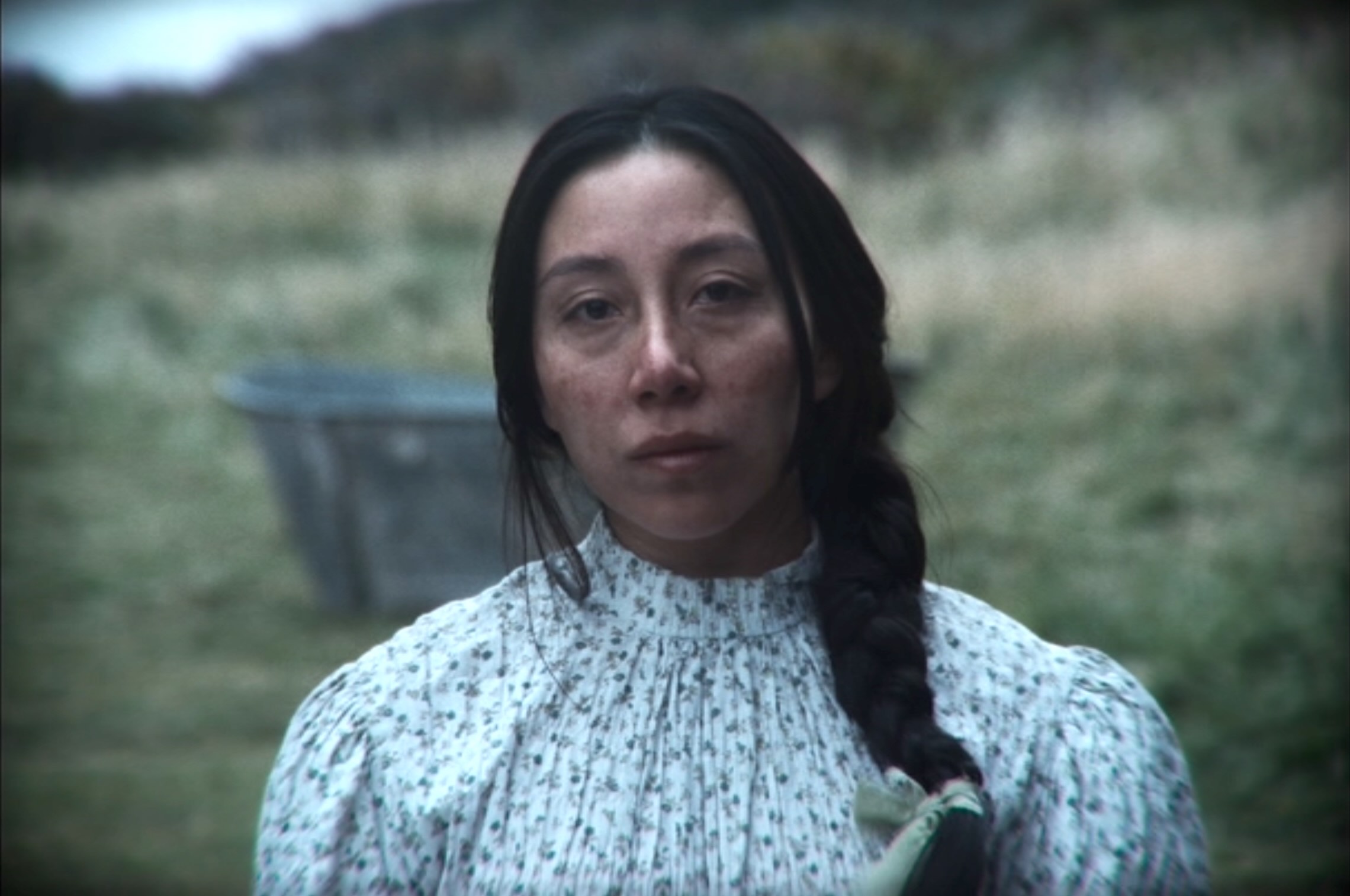 Photo portrait of a person standing in front of a grassy hill.