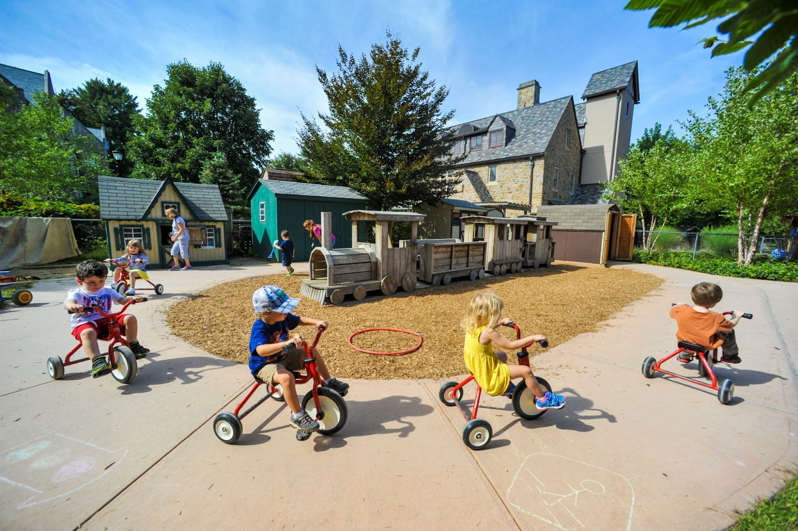 Children riding tricycles on a sidewalk.