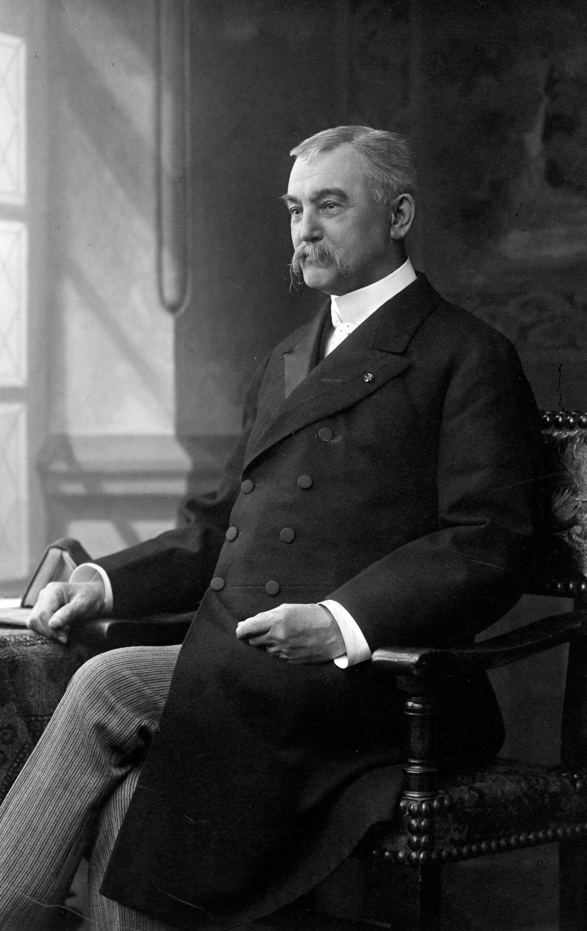 A vintage, sepia-toned studio portrait of a person from the mid-19th century wearing a dark, formal jacket and a high-collared shirt with a necktie.