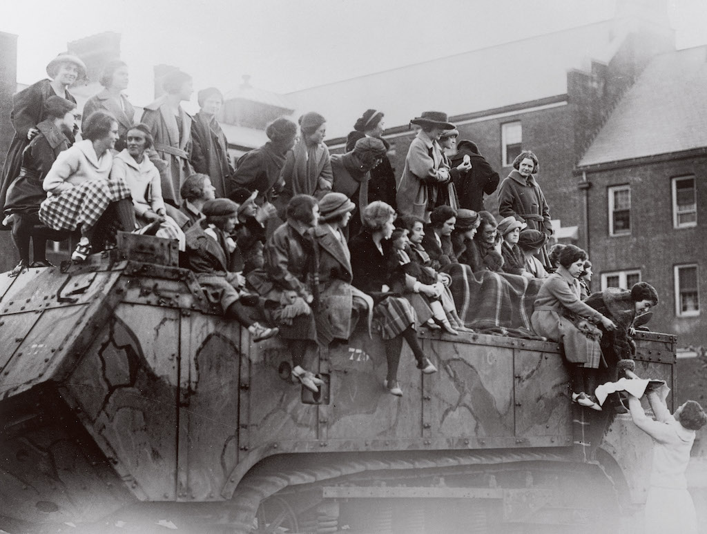 An archival photo of a group of students sitting together on top of a WWI French tank..