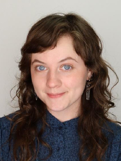 A photo of Cassidy Meurer, a person with medium-length, brown, wavy hair. The individual wears a dark blue shirt adorned with a subtle pattern.
